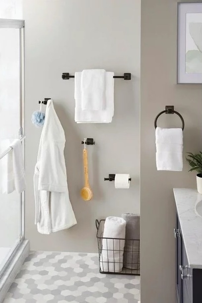 A tidy bathroom wall featuring a shower door, towel racks with white towels, a toilet paper holder, and a bath brush