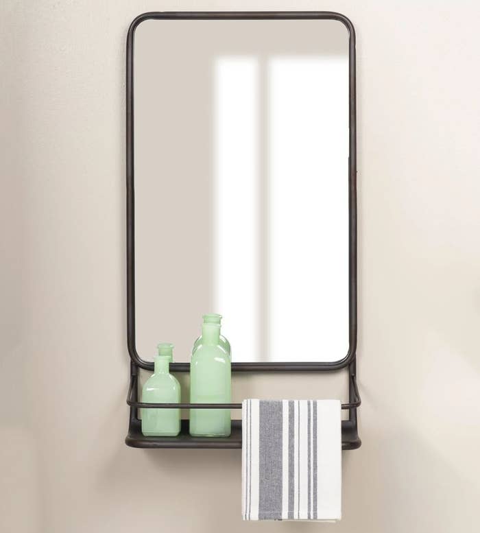 black hanging mirror with small bottles and towel