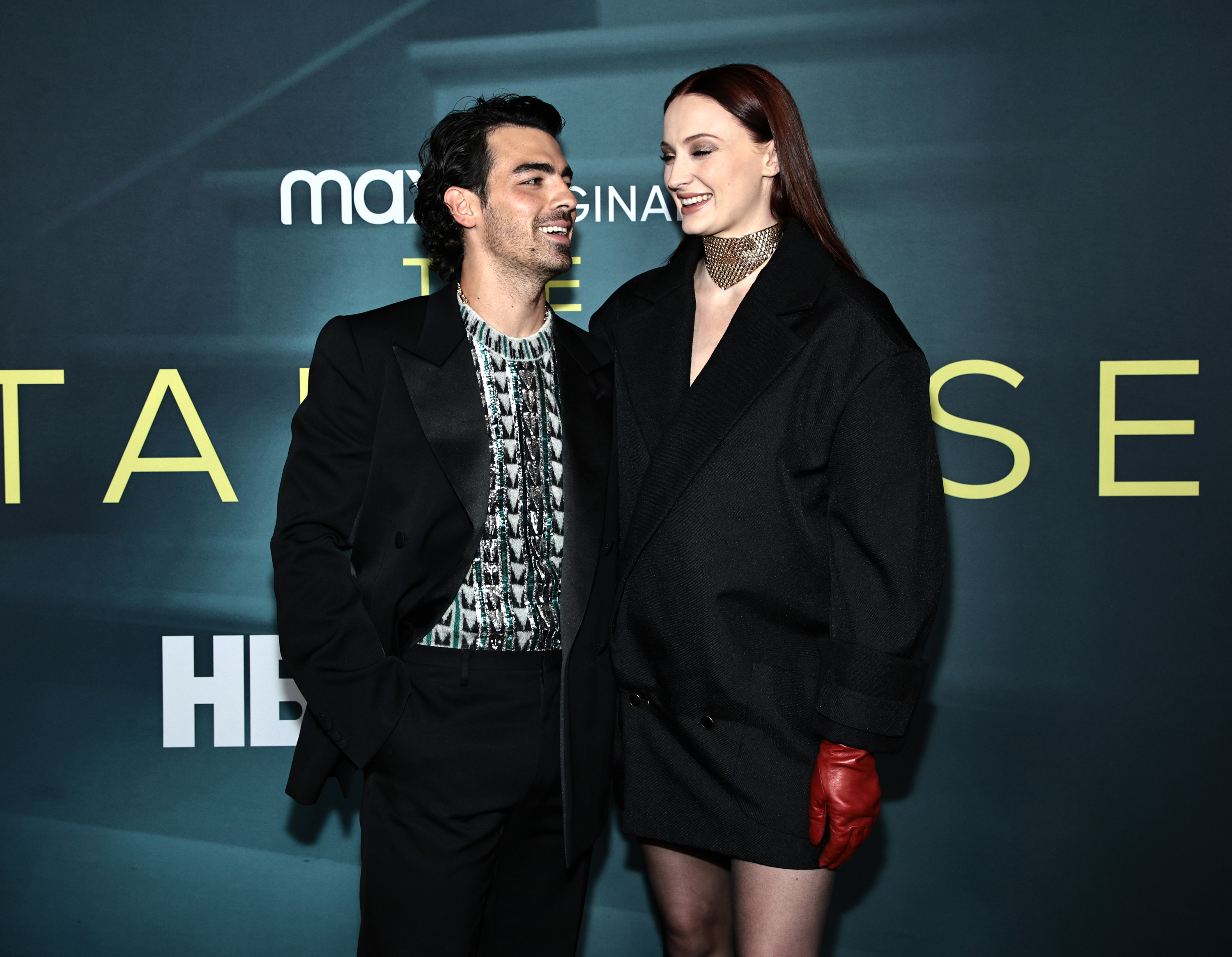 Joe Jonas and Sophie Turner looking at each other as they stand on the red carpet at a premiere event