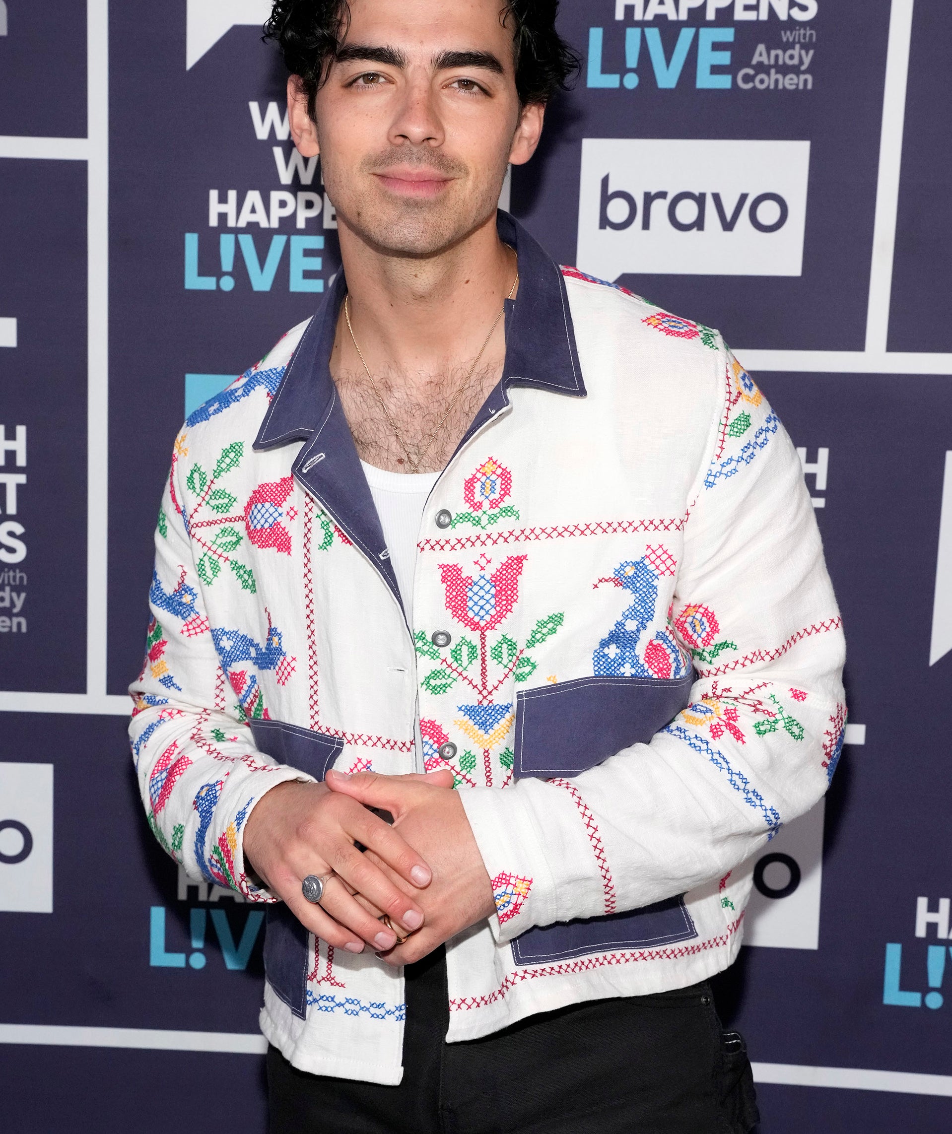 Joe Jonas smiles for the cameras on the red carpet while wearing an embroidered jacket