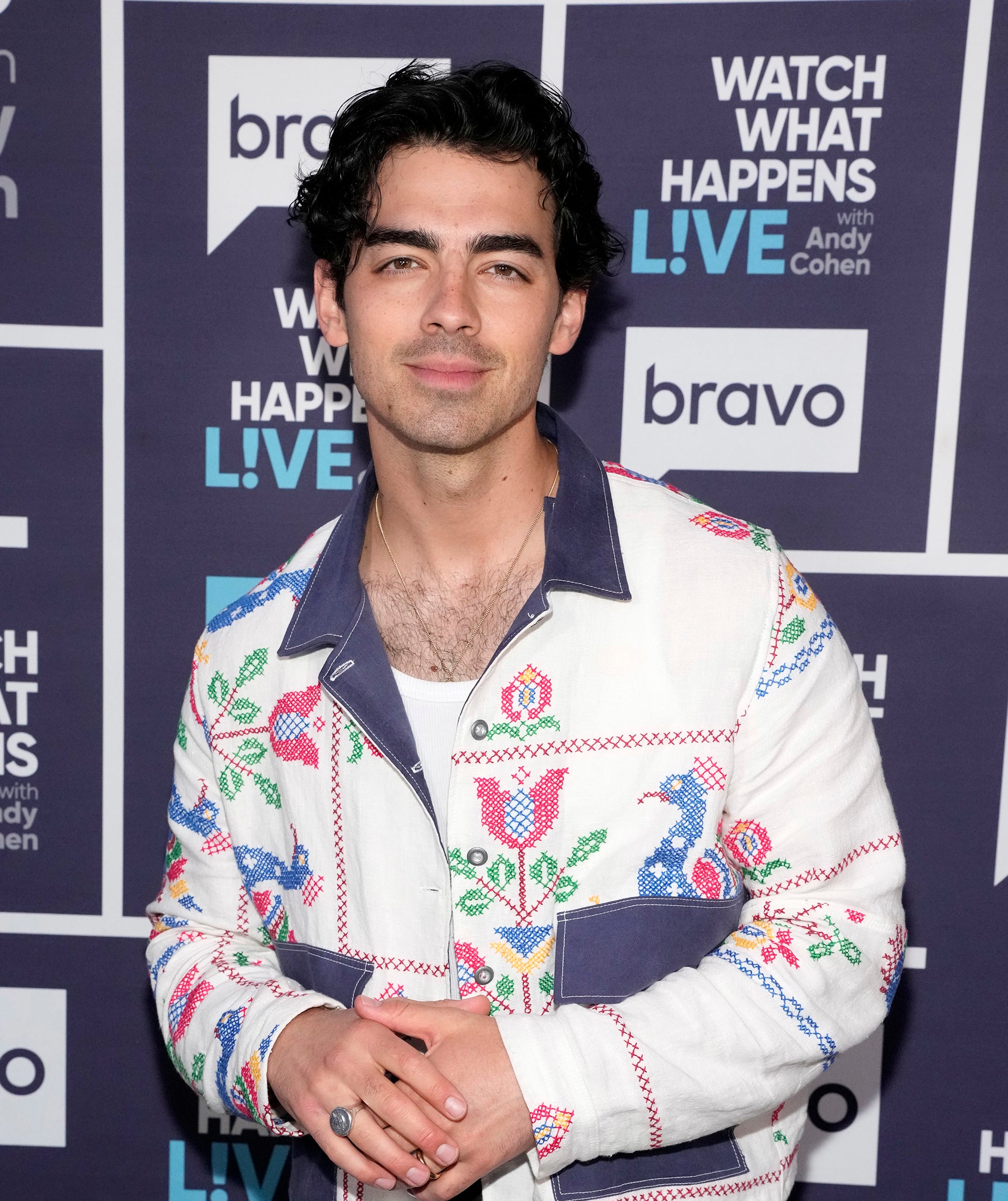 Joe Jonas smiles for the cameras on the red carpet while wearing an embroidered jacket