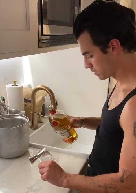 Joe Jonas measuring out liquor for a cocktail by a sink