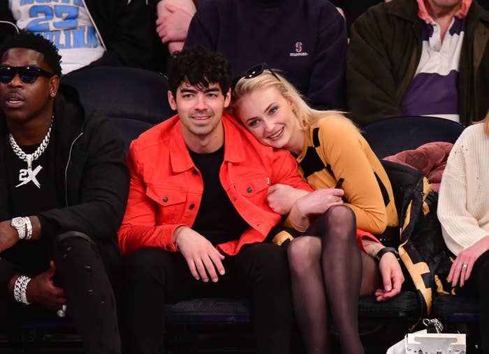 The couple cuddling as they sit courtside at a sports event