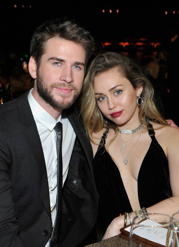 Liam Hemsworth and Miley Cyrus lean into each other as they pose for a photo at an event