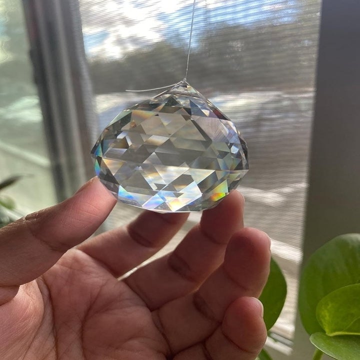 a hand holding the crystal suncatcher