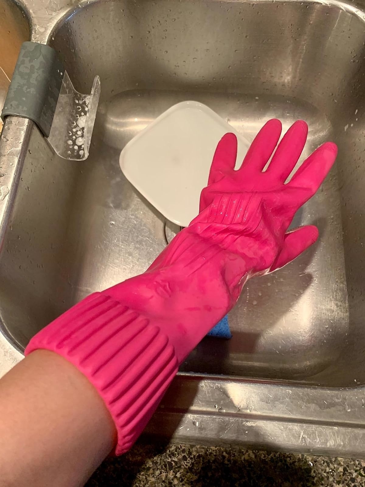 Reviewer wearing the pink cleaning glove near their sink