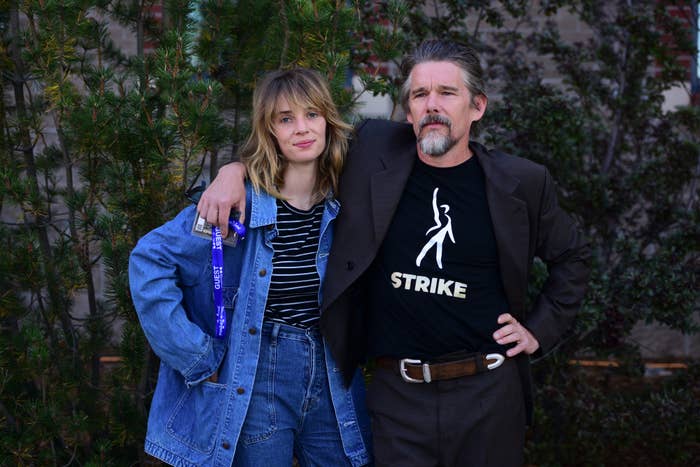 Closeup of Ethan, who&#x27;s wearing a shirt that says &quot;Strike&quot; with his arm around Maya