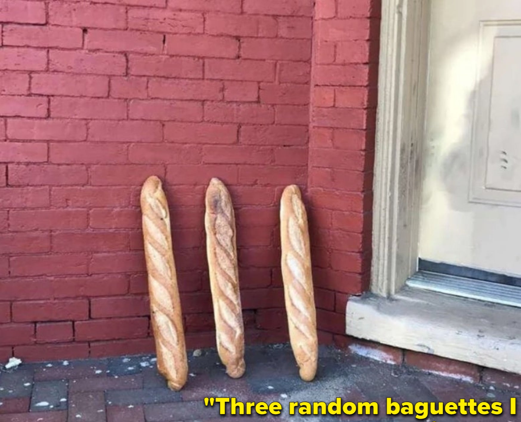 Three random baguettes are chilling outside, leaning against a brick wall