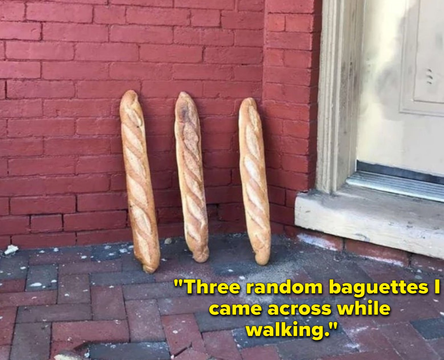 Three random baguettes are chilling outside, leaning against a brick wall