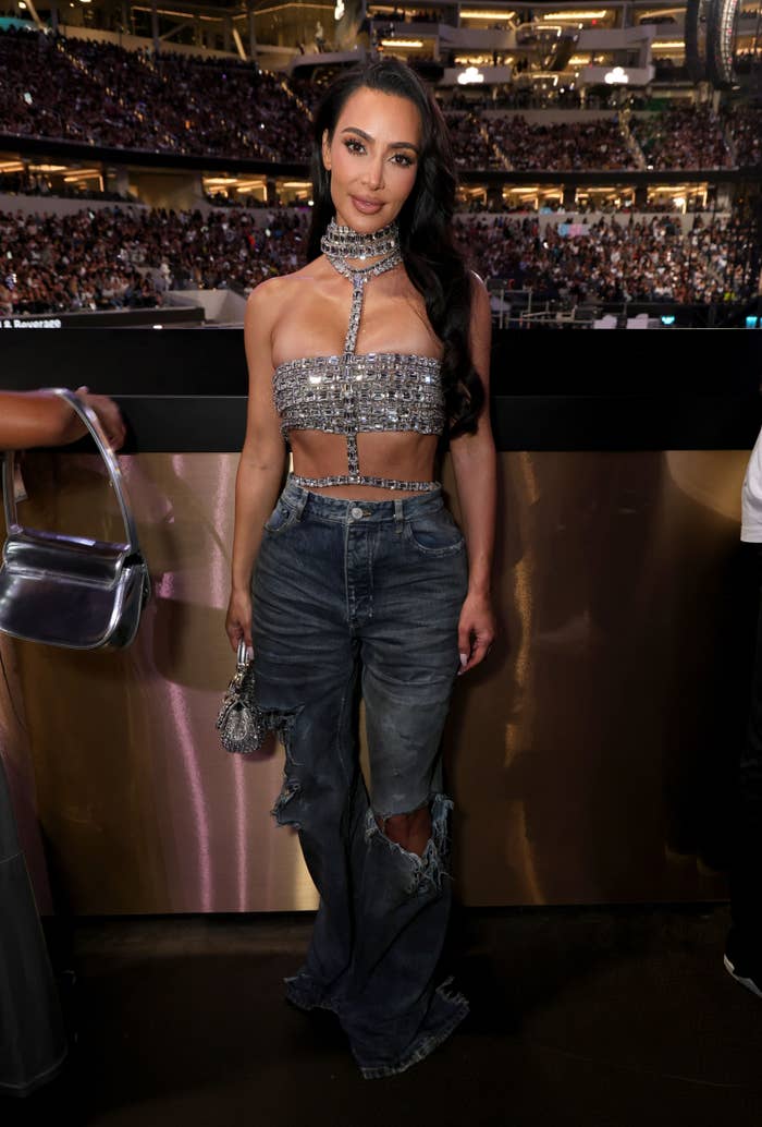 A closeup of Kim Kardashian in a bejeweled tube top and ripped jeans