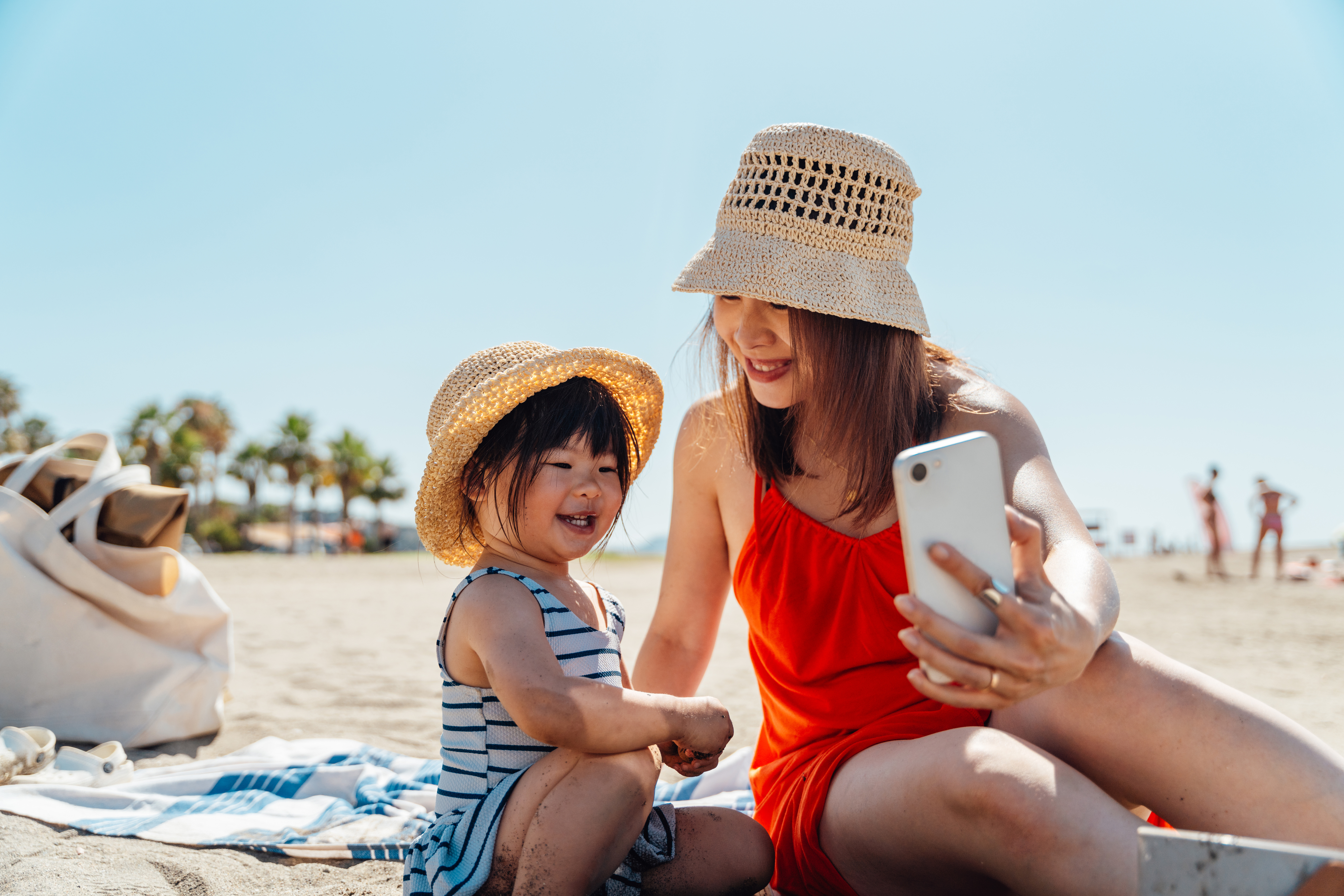 a mother taking a photo with her child on the beach