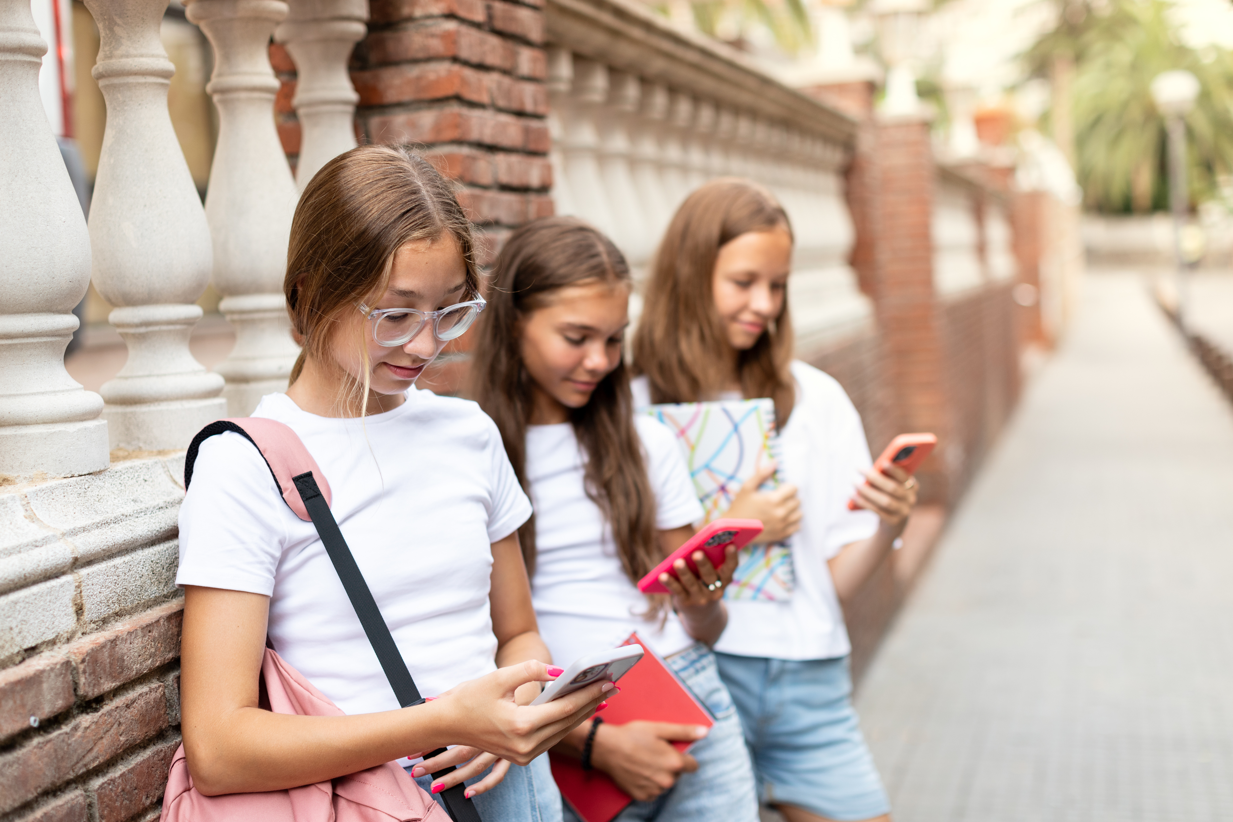 three young children on their phones