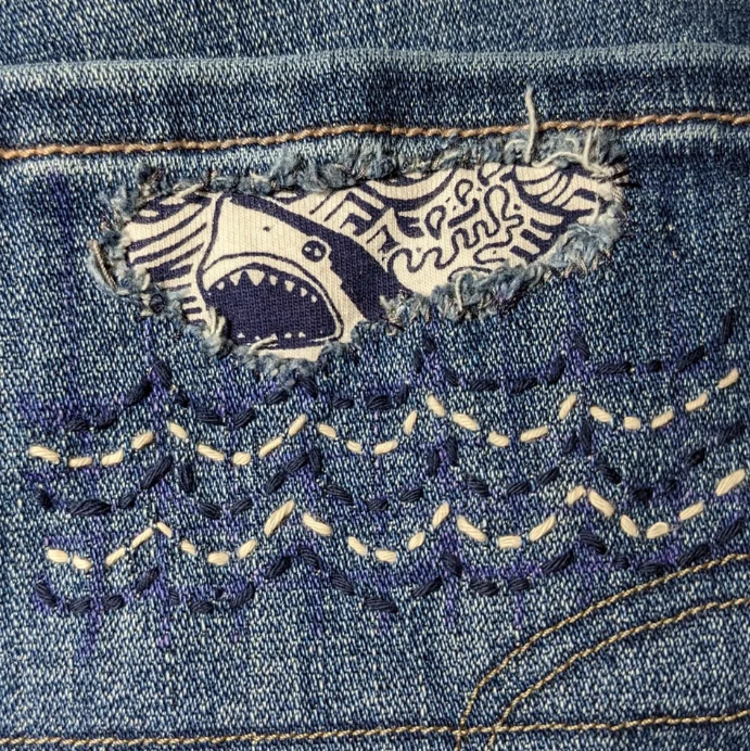 shark and stitches made to look like waves on a jean pocket