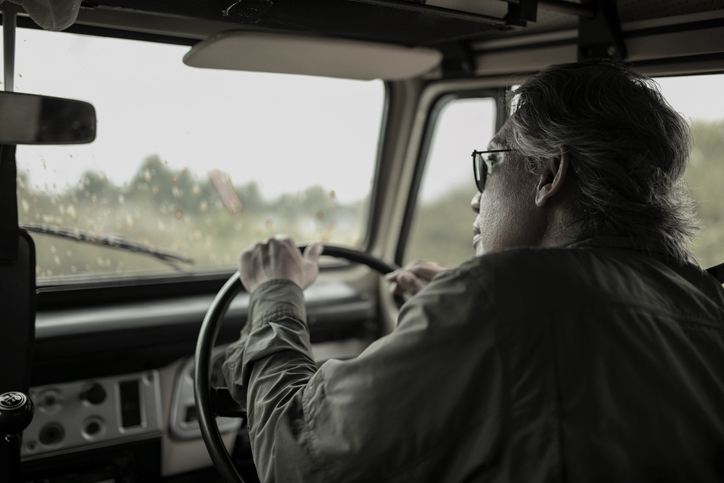 Rear view of senior man in off-road vehicle on road