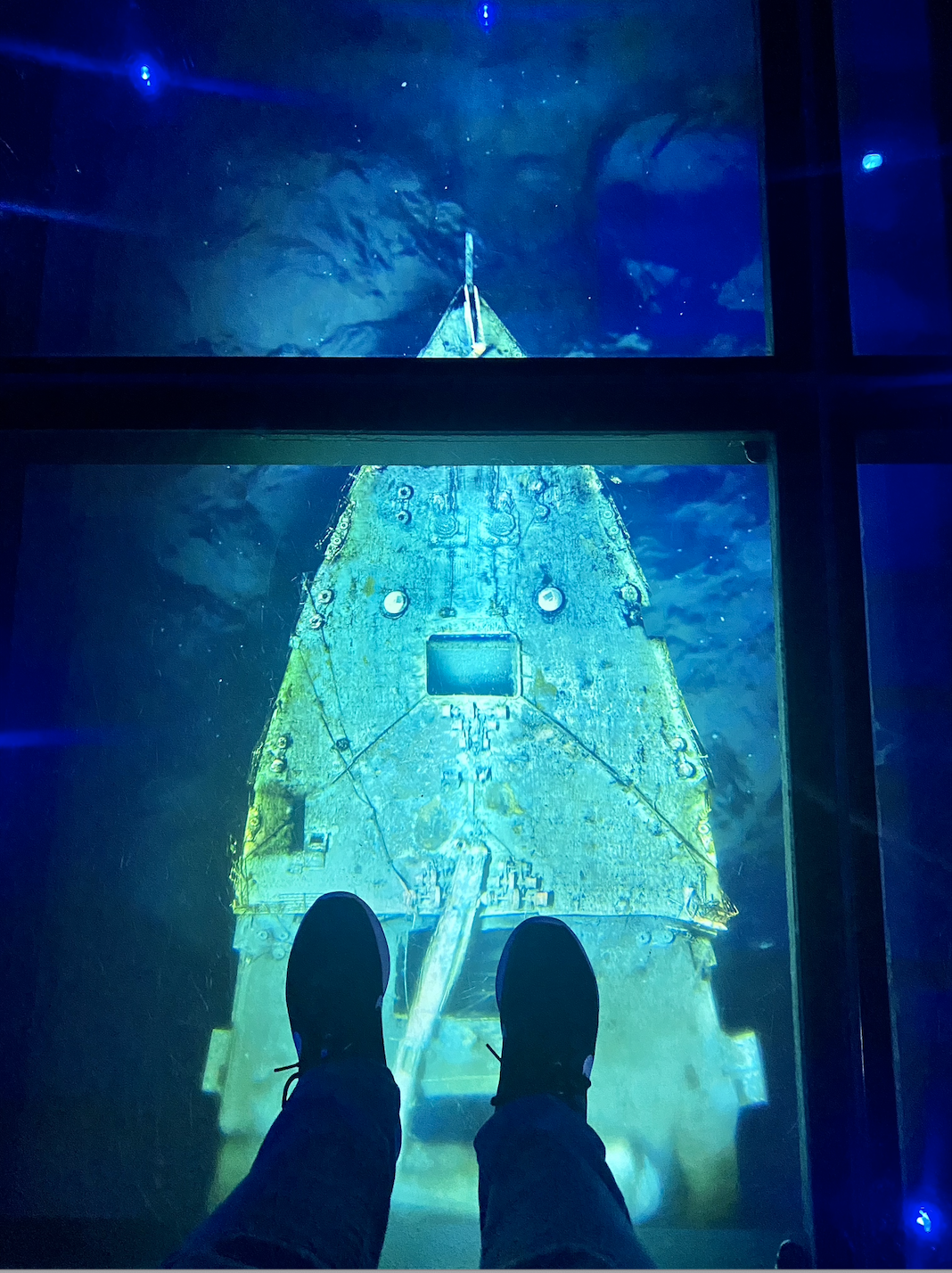 someone standing on glass flooring with the sunken ship below