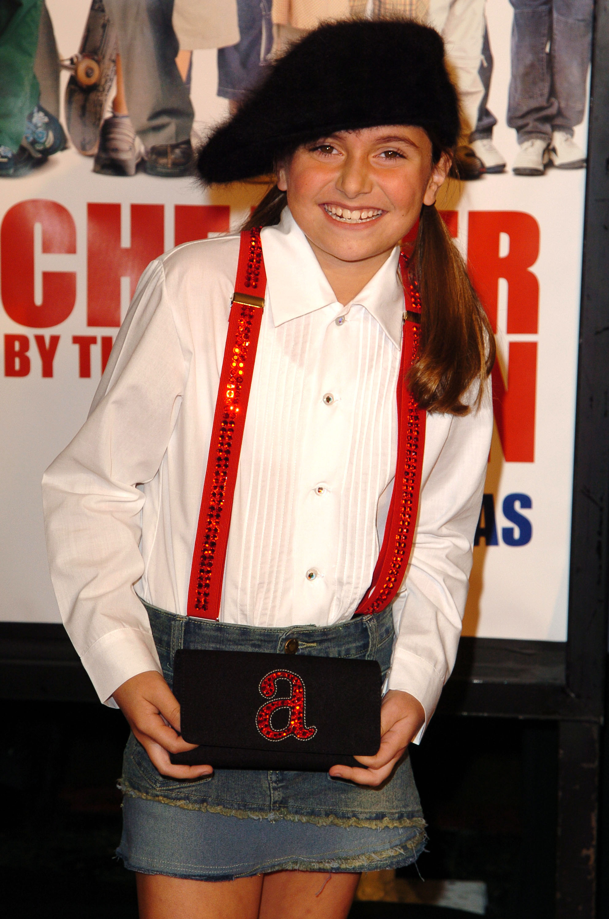 Smiling Alyson wearing a fuzzy hat and a denim skirt with suspenders