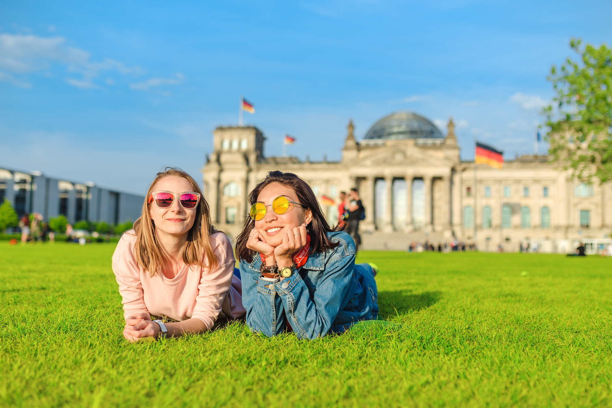 Two girls laying on the lawn in Germany with German flags in the background