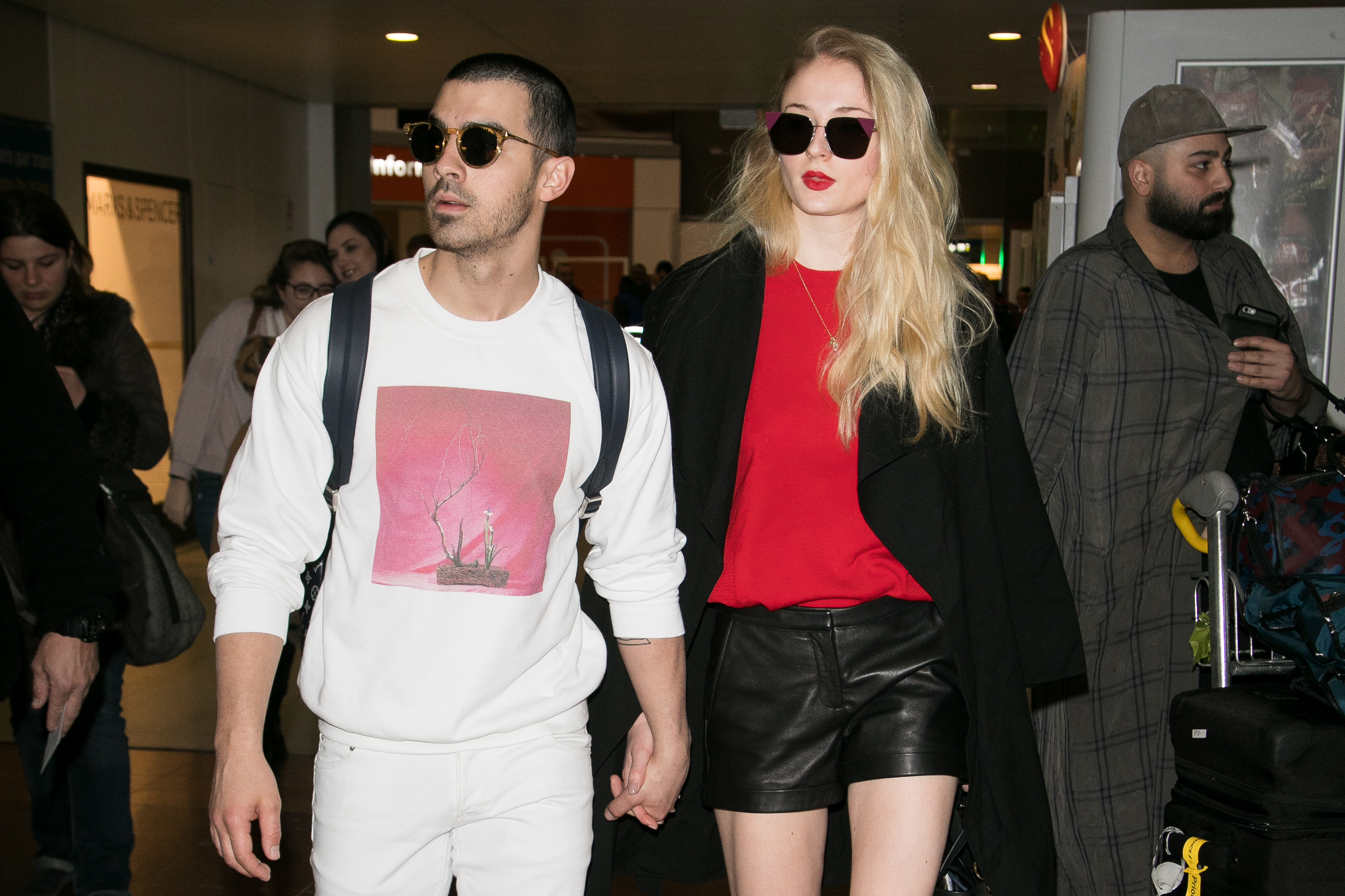 Joe and Sophie walking through the airport hand-in-hand