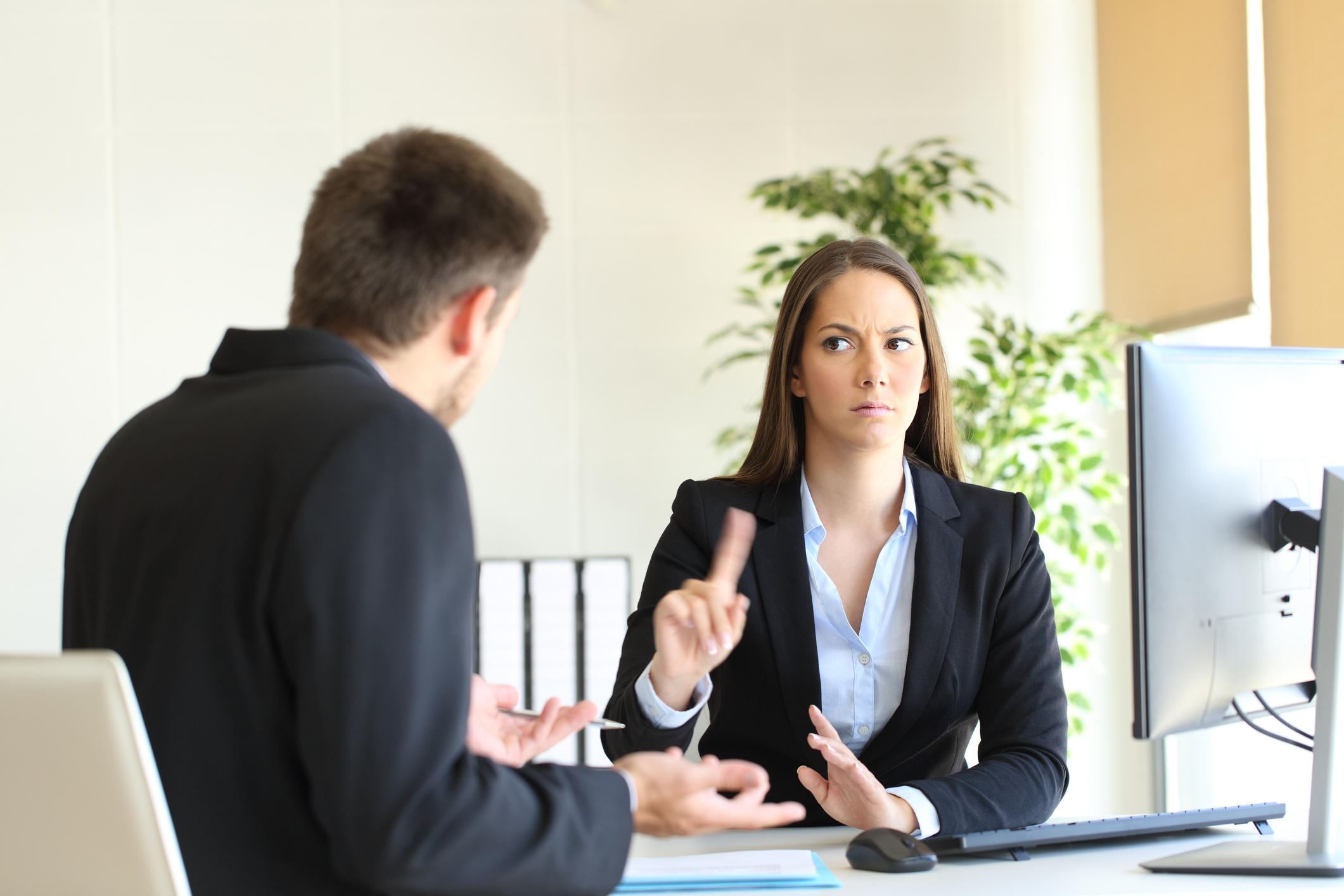 A woman raising her finger to a man in an office