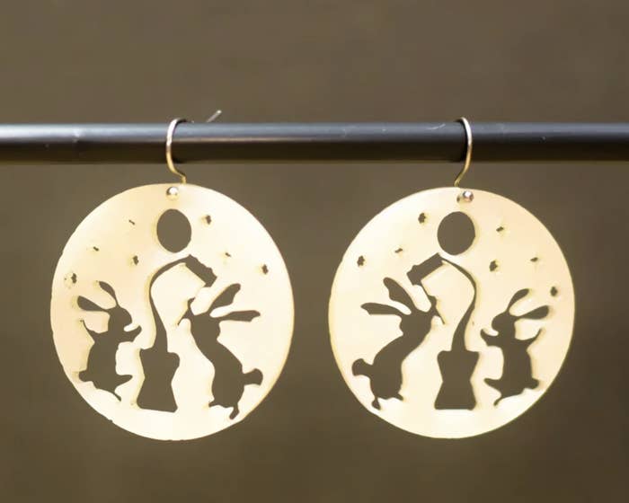 A pair of pearl colored earrings featuring bunnies making mochi on the moon.