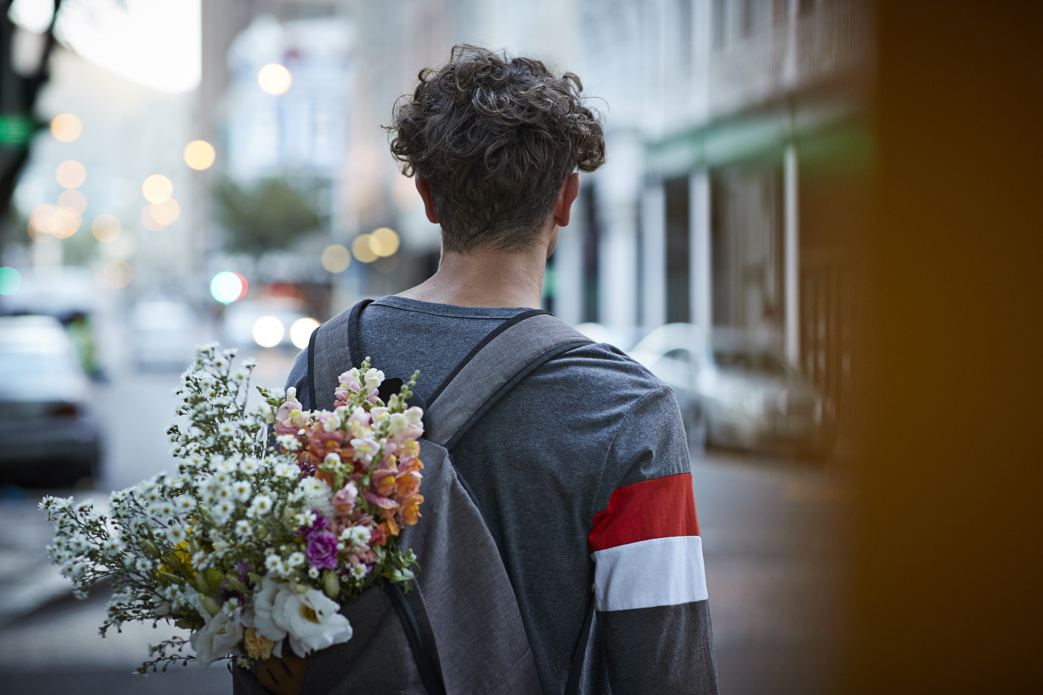A guy is carrying a bouquet of flowers in his backpack
