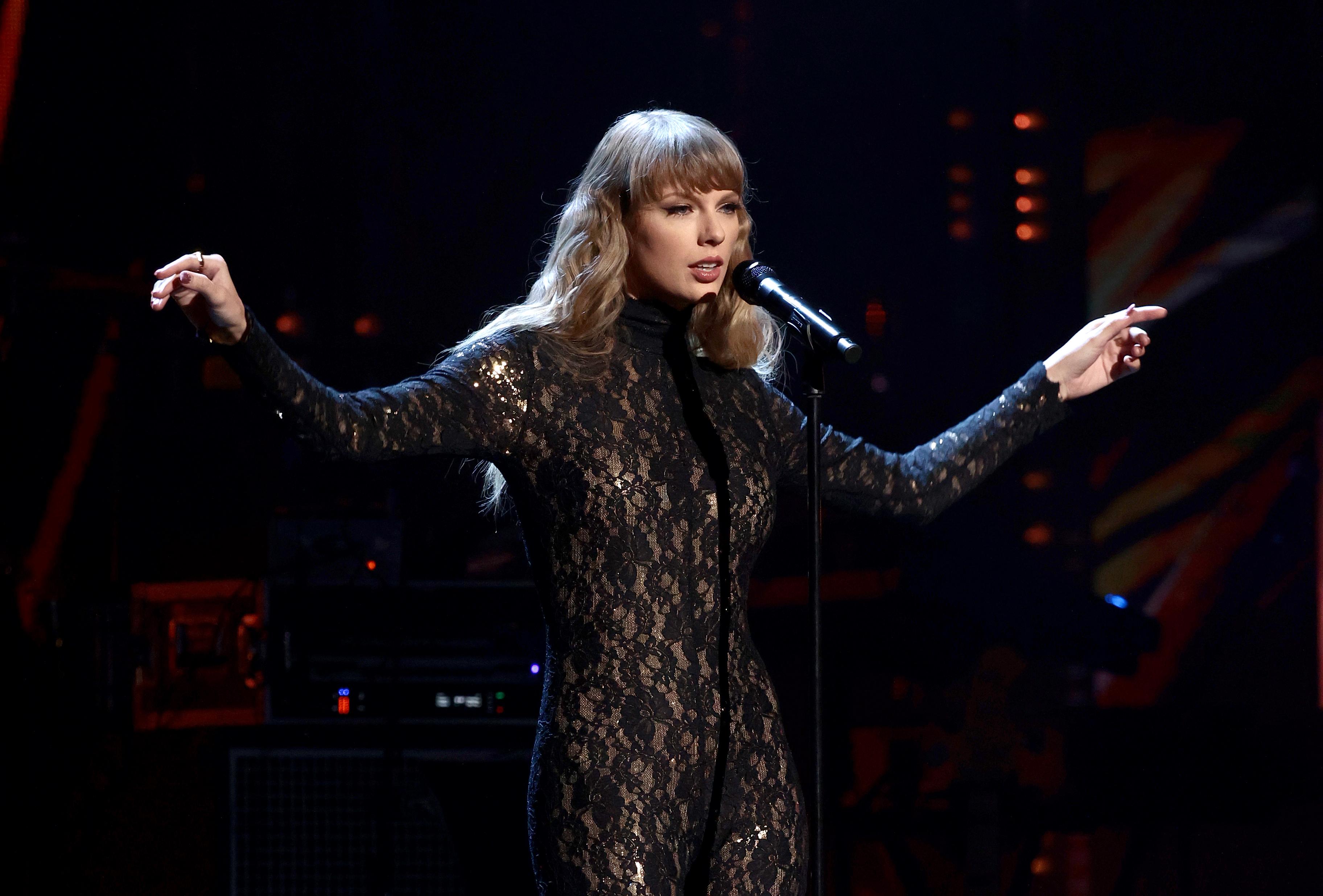 Taylor performing onstage in a lacy turtleneck bodysuit