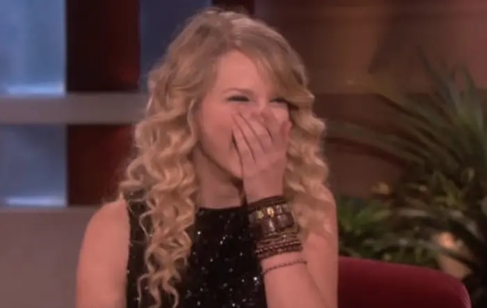 Taylor on the talk show covering her mouth and laughing