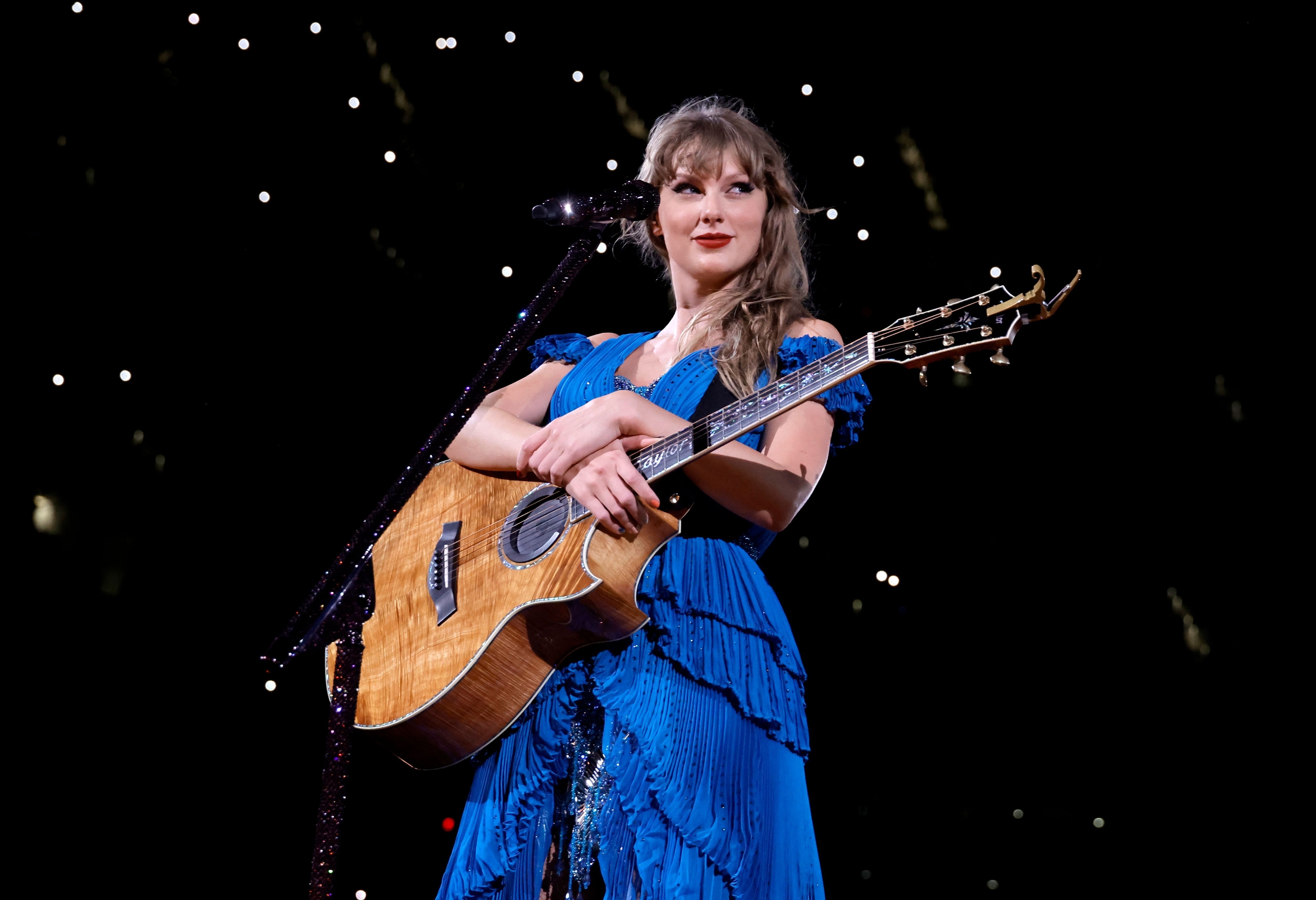 Taylor smiling onstage with a guitar