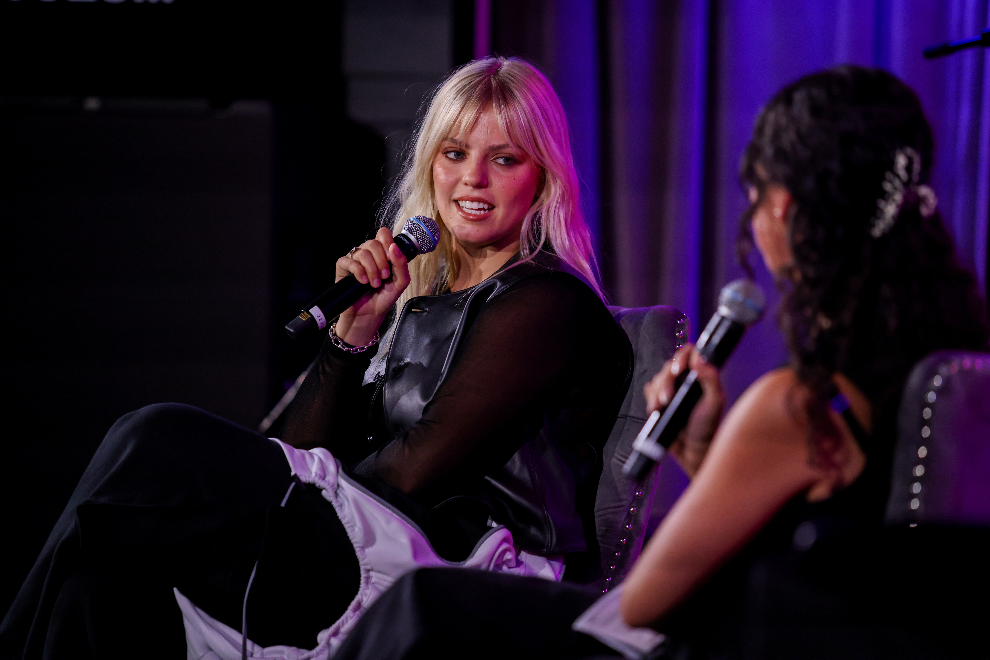 Close-up of Reneé sitting onstage holding a microphone