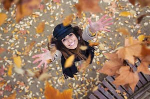 a girl throwing fall leaves in the air and smiling