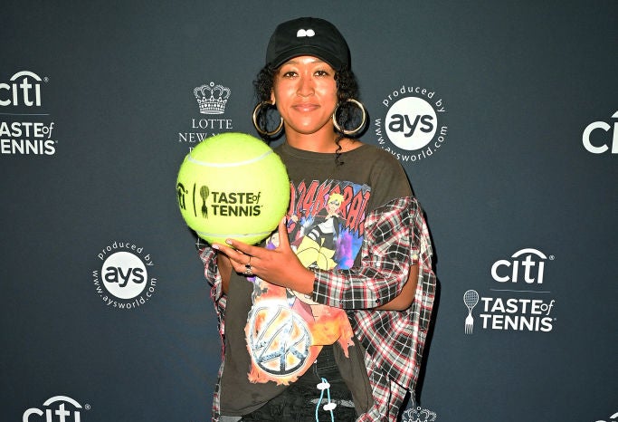 Naomi Osaka holding a huge tennis ball that says &quot;Taste of Tennis&quot; for an event