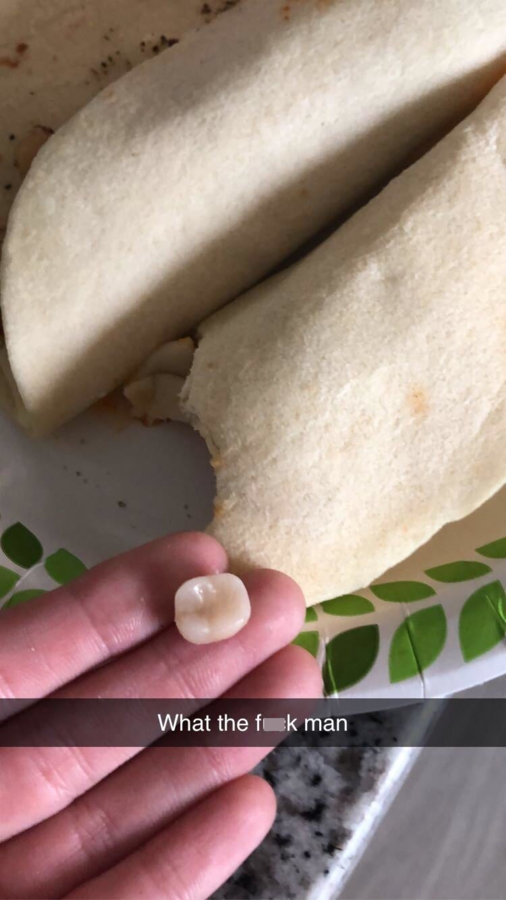 A person holds up a broken tooth above two flour tortillas
