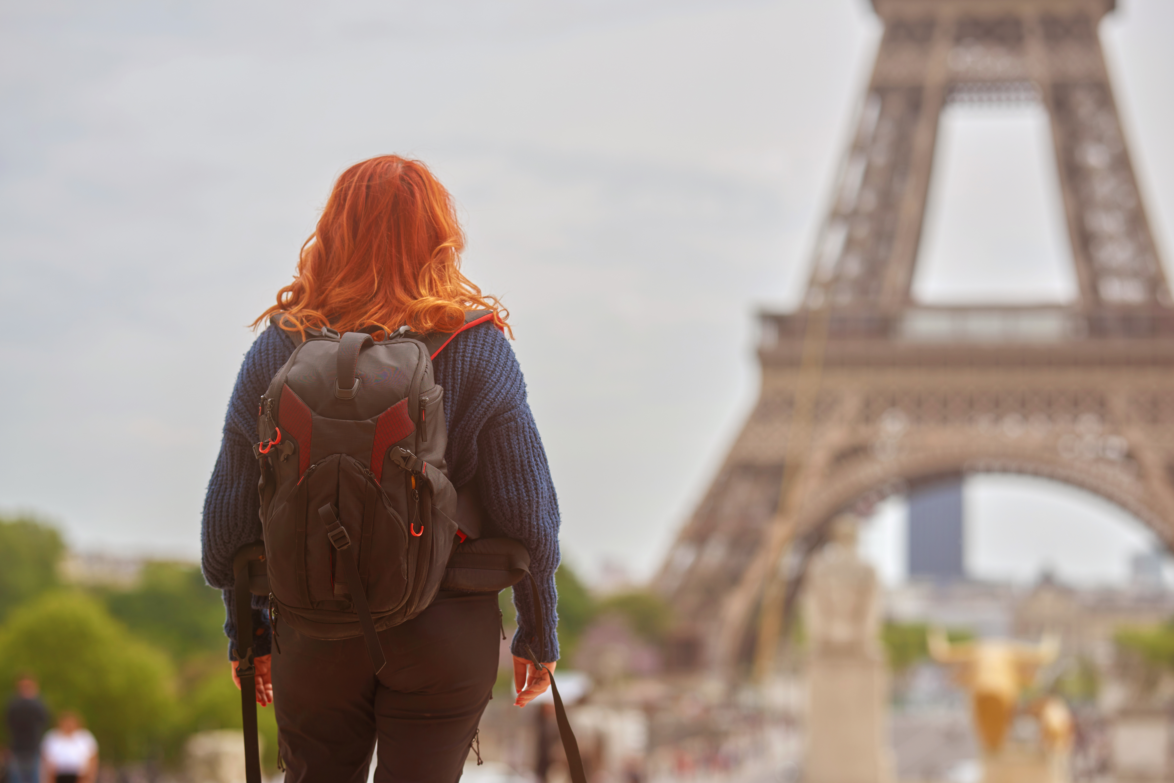 someone standing in front of the eiffel tower with a backpack on