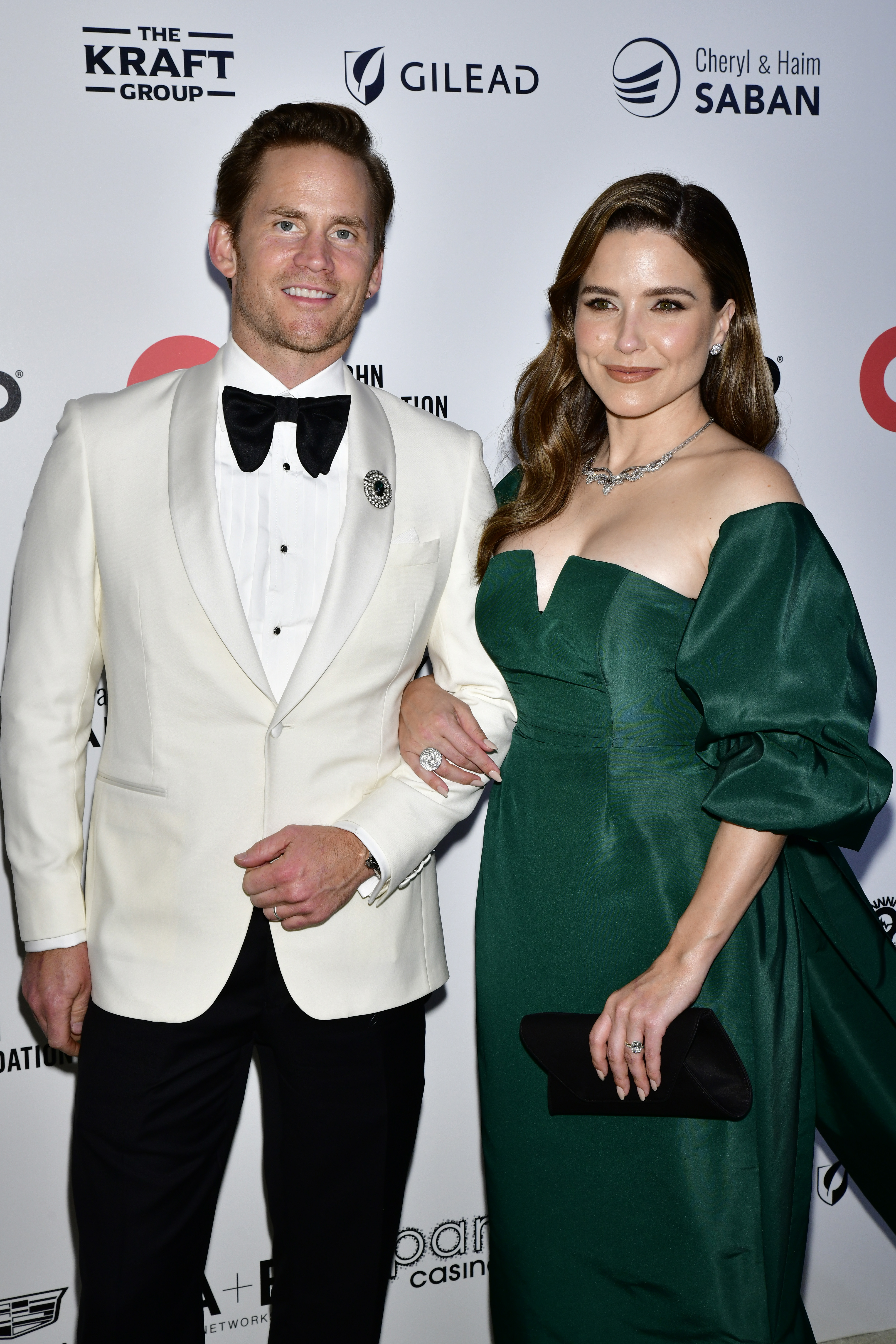 A closeup of Grant Hughes and Sophia Bush arm-in-arm at formal event
