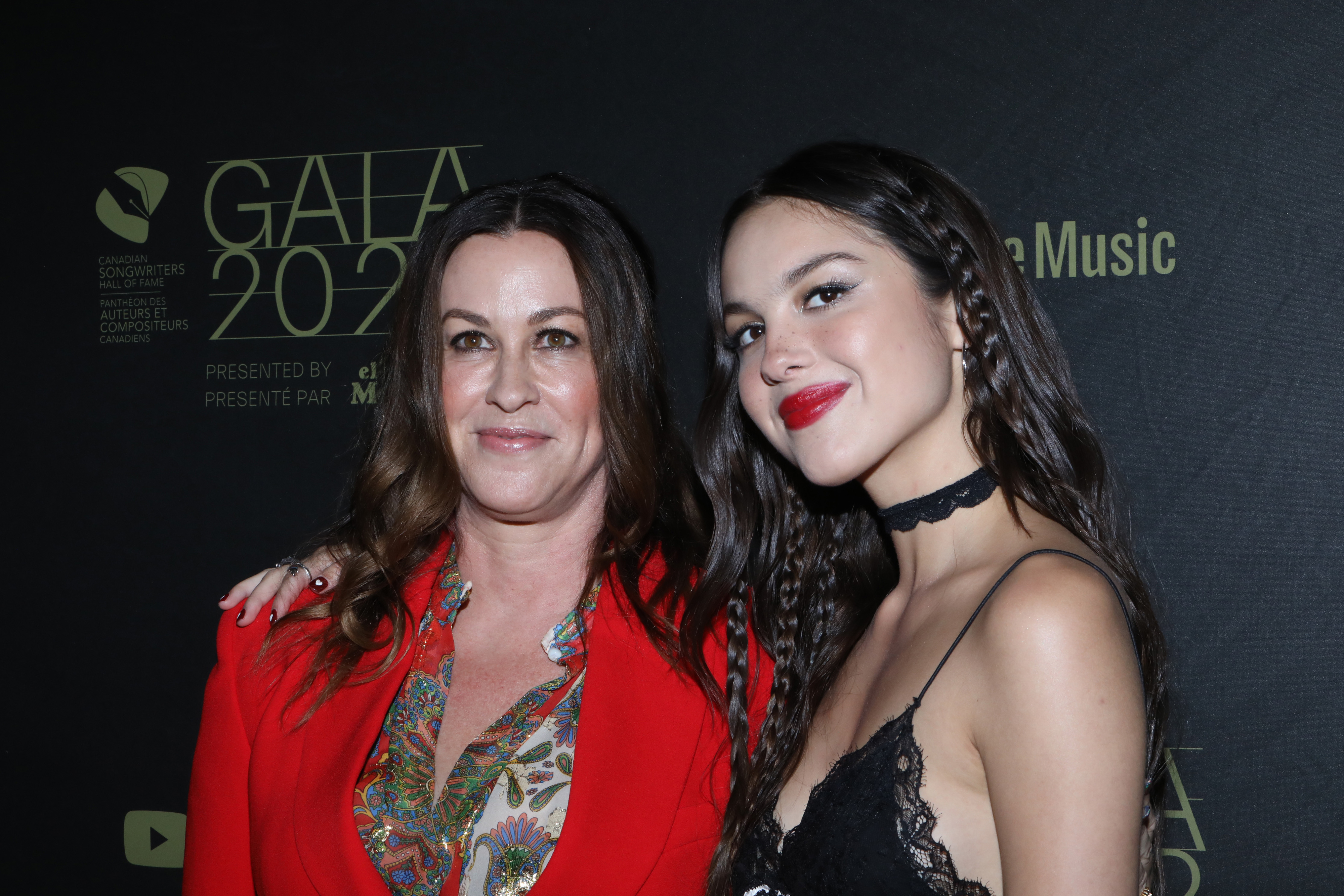 Olivia with her arm around Alanis Morissette&#x27;s shoulder as they smile for photographers on the red carpet of an event