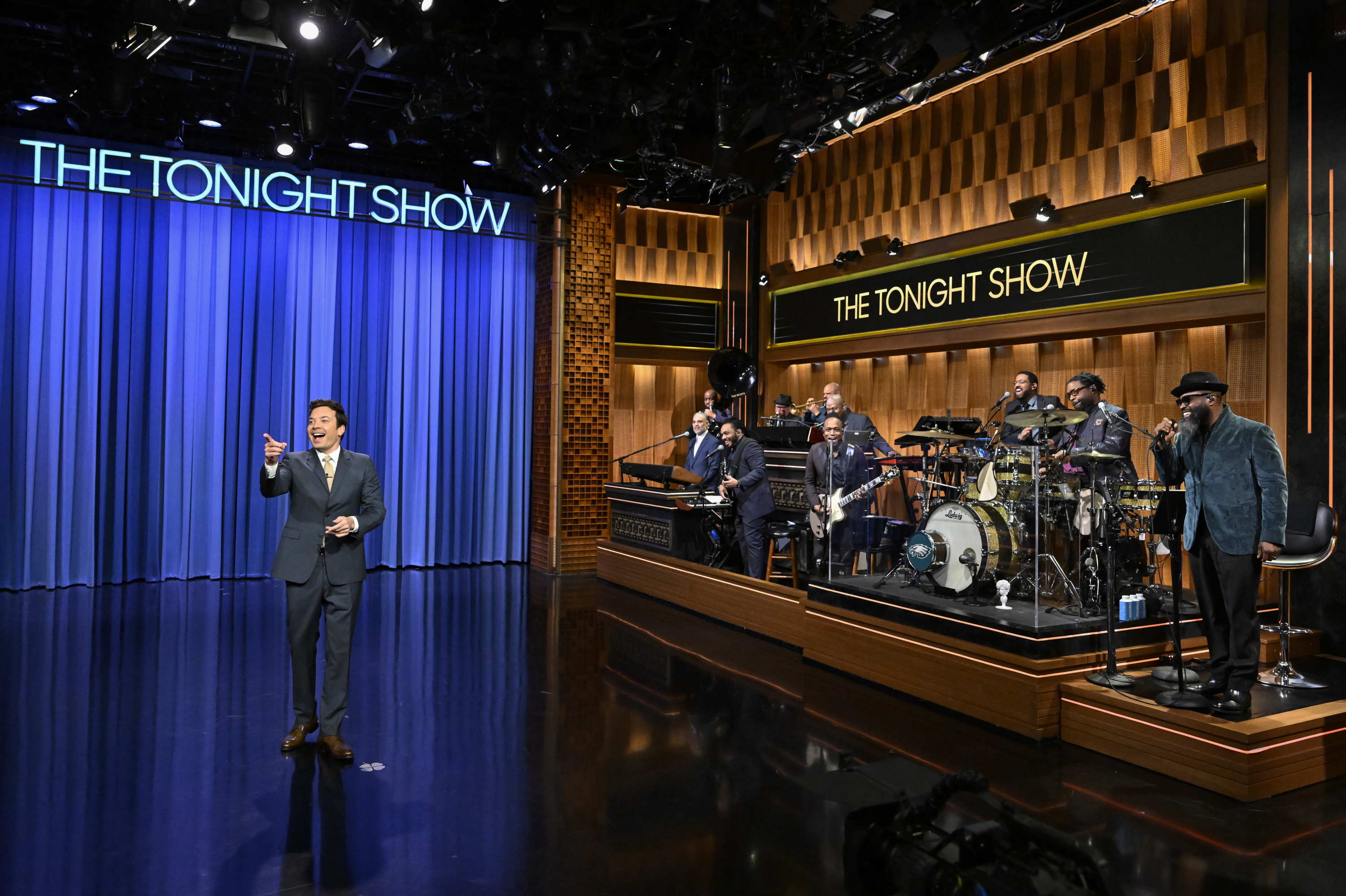 Jimmy Fallon stands next to The Tonight Show house band, the Roots