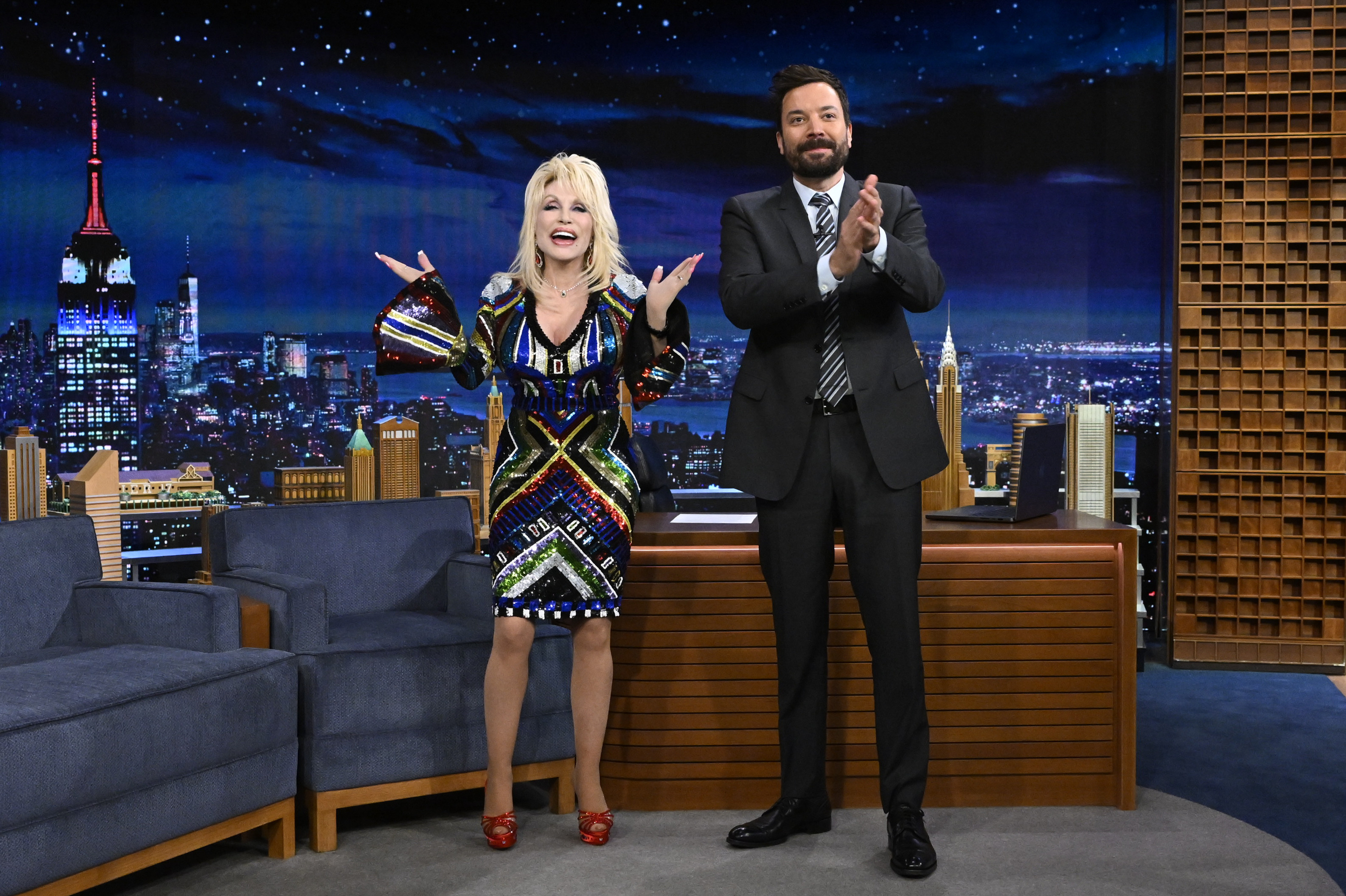 A bearded Jimmy Fallon applauds as he stands next to Dolly Parton on The Tonight Show