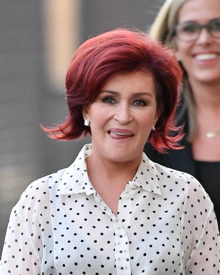 Close-up of Sharon smiling in a blouse as she walks outside