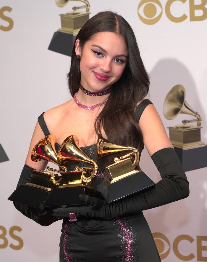 Olivia Rodrigo holding her three grammys