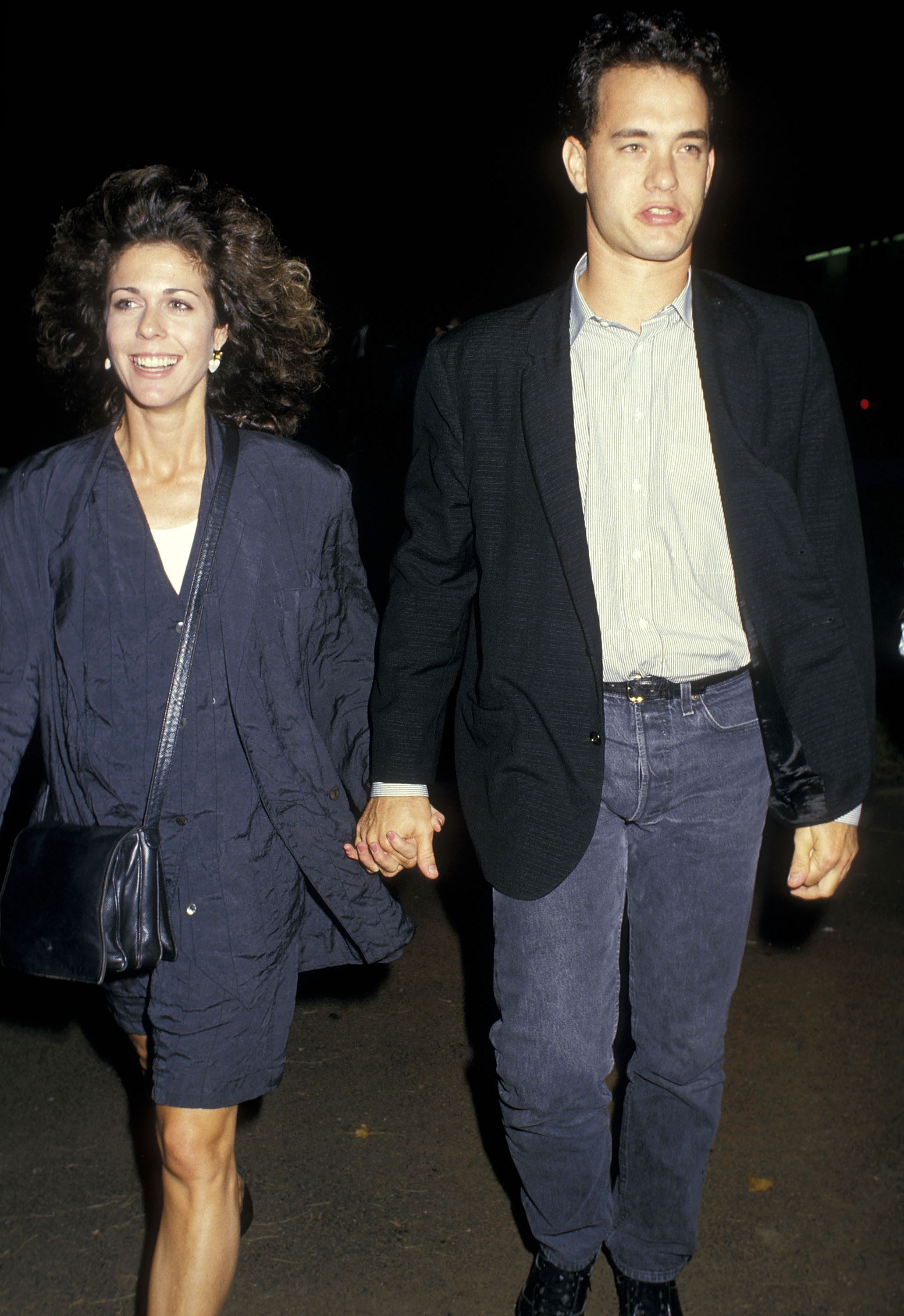 Rita Wilson and Tom Hanks hold hands as they walk outside at night