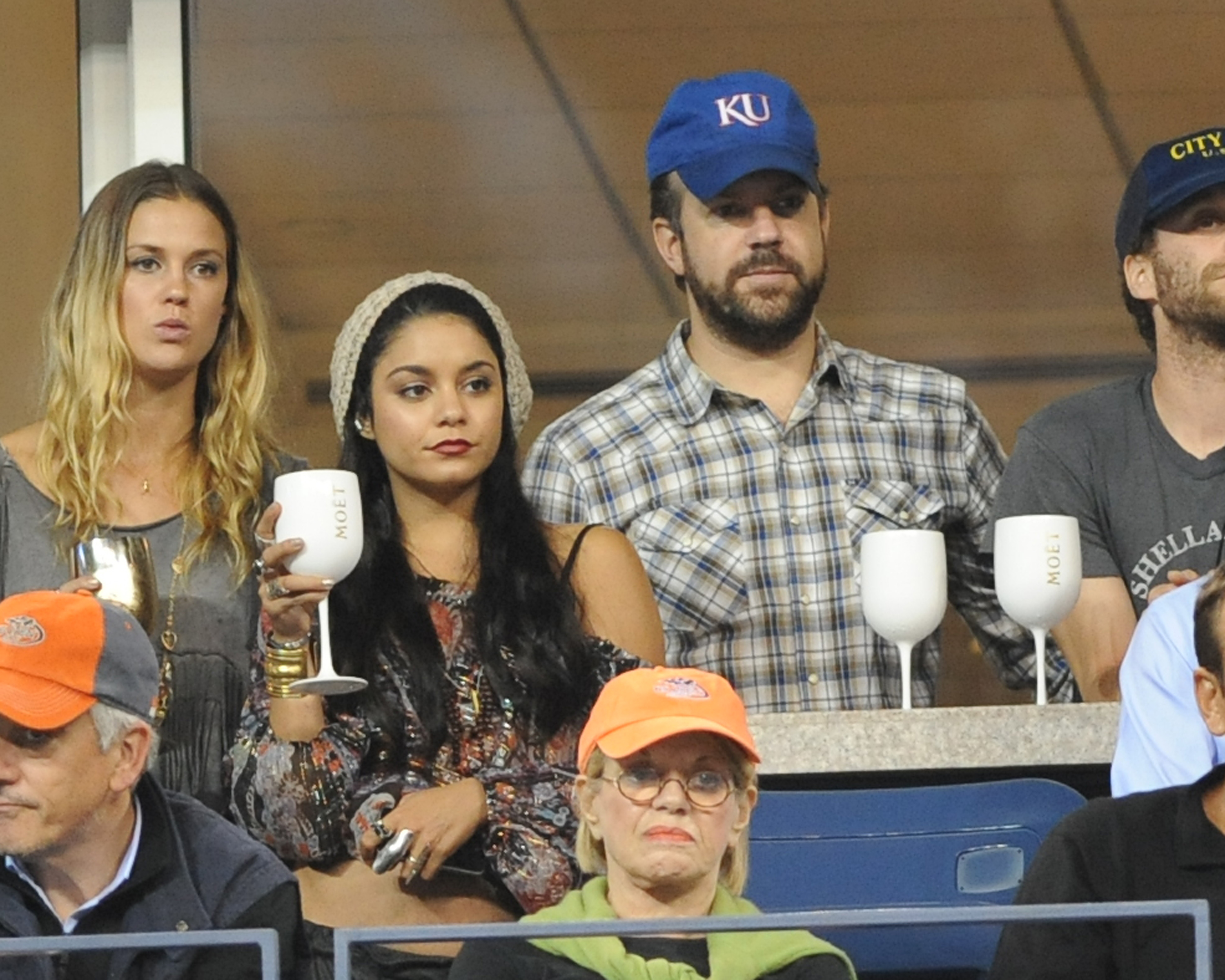 Vanessa Hudgens watches a match while holding a large glass with &quot;Moet&quot; on it, while Jason Sudeikis stands in the suite behind her holding a tray with two more matching glasses