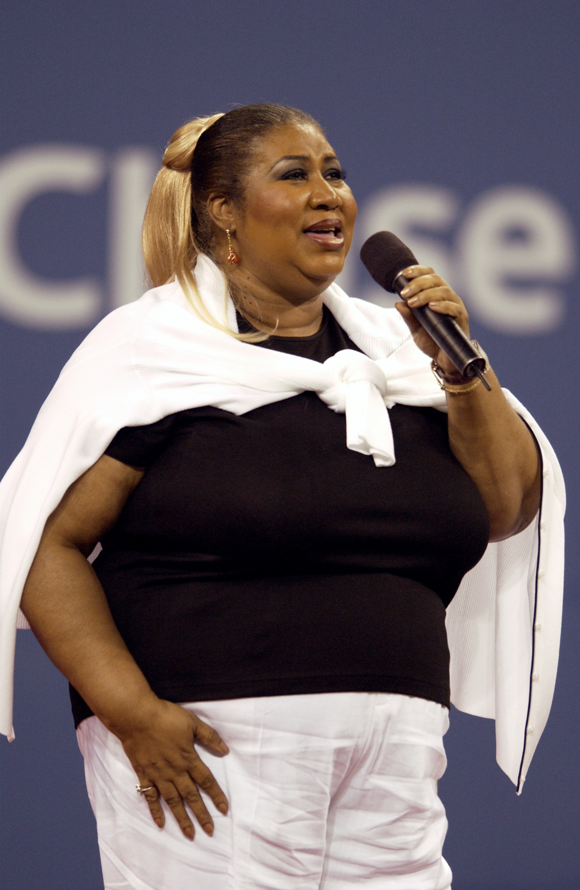 Aretha Franklin holding a microphone and singing on court at the US Open