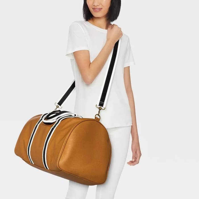 model wearing brown weekender bag with stripe design