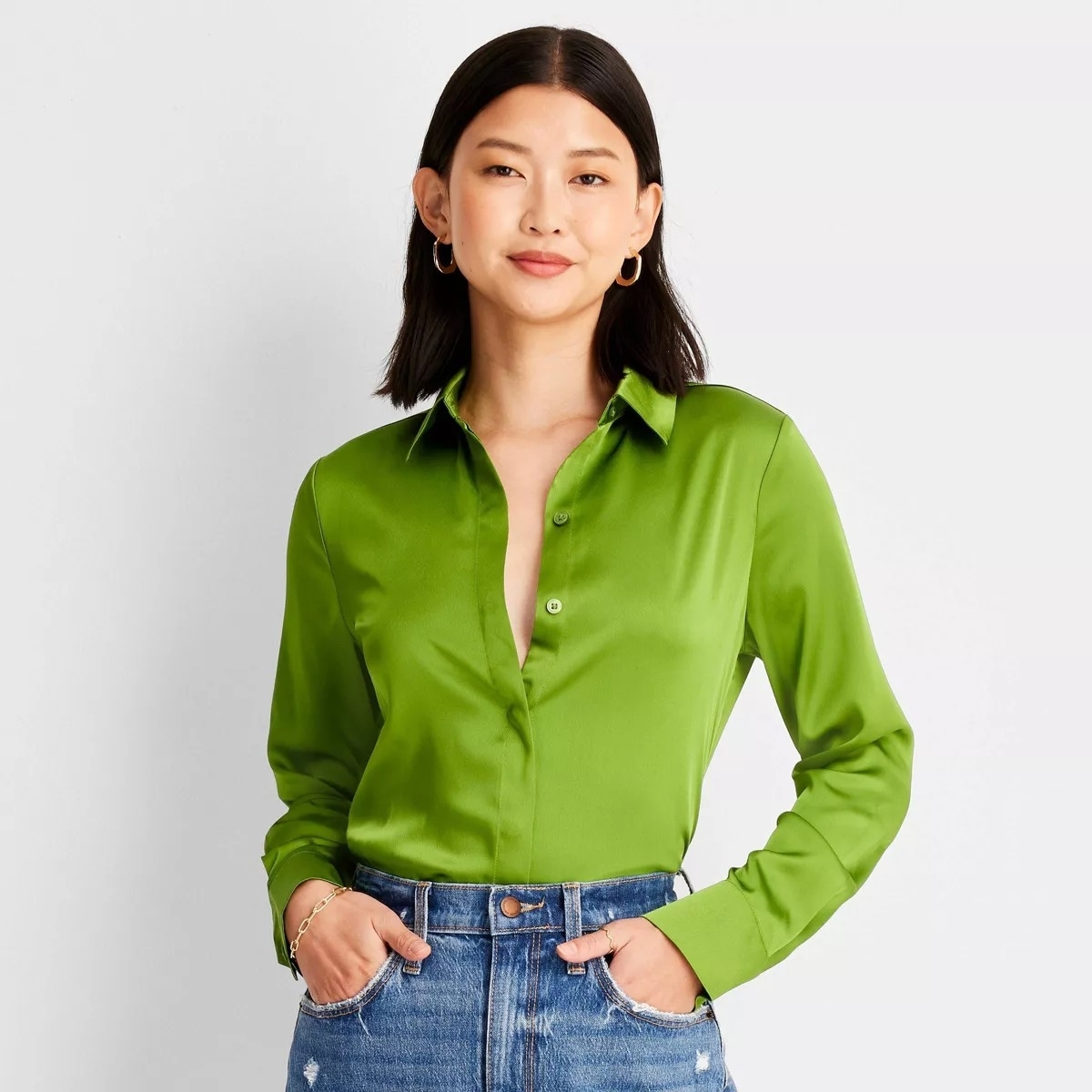 model wearing green long-sleeve button-front shirt with blue jeans