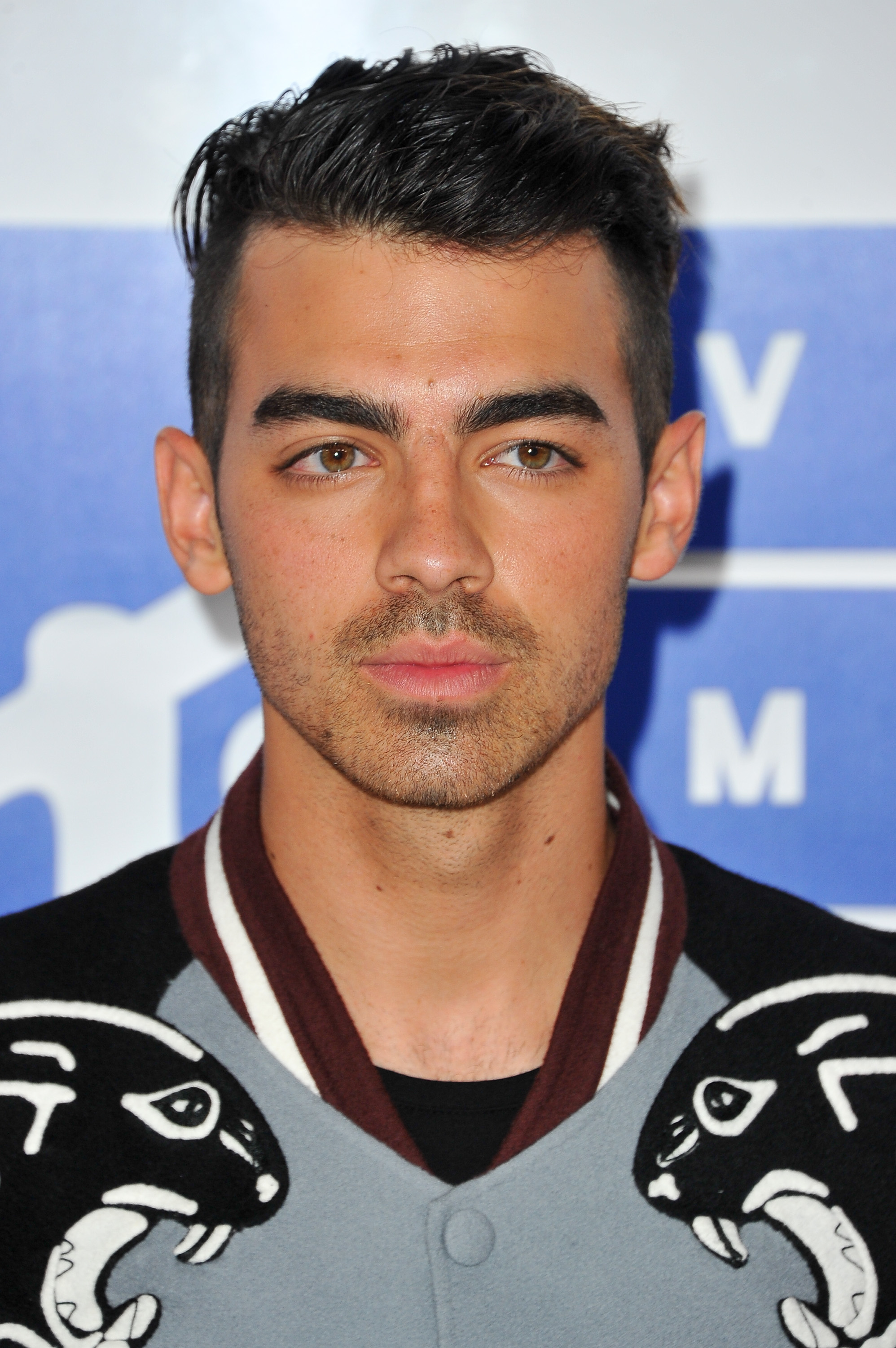 A closeup of Joe Jonas in a letterman-style jacket