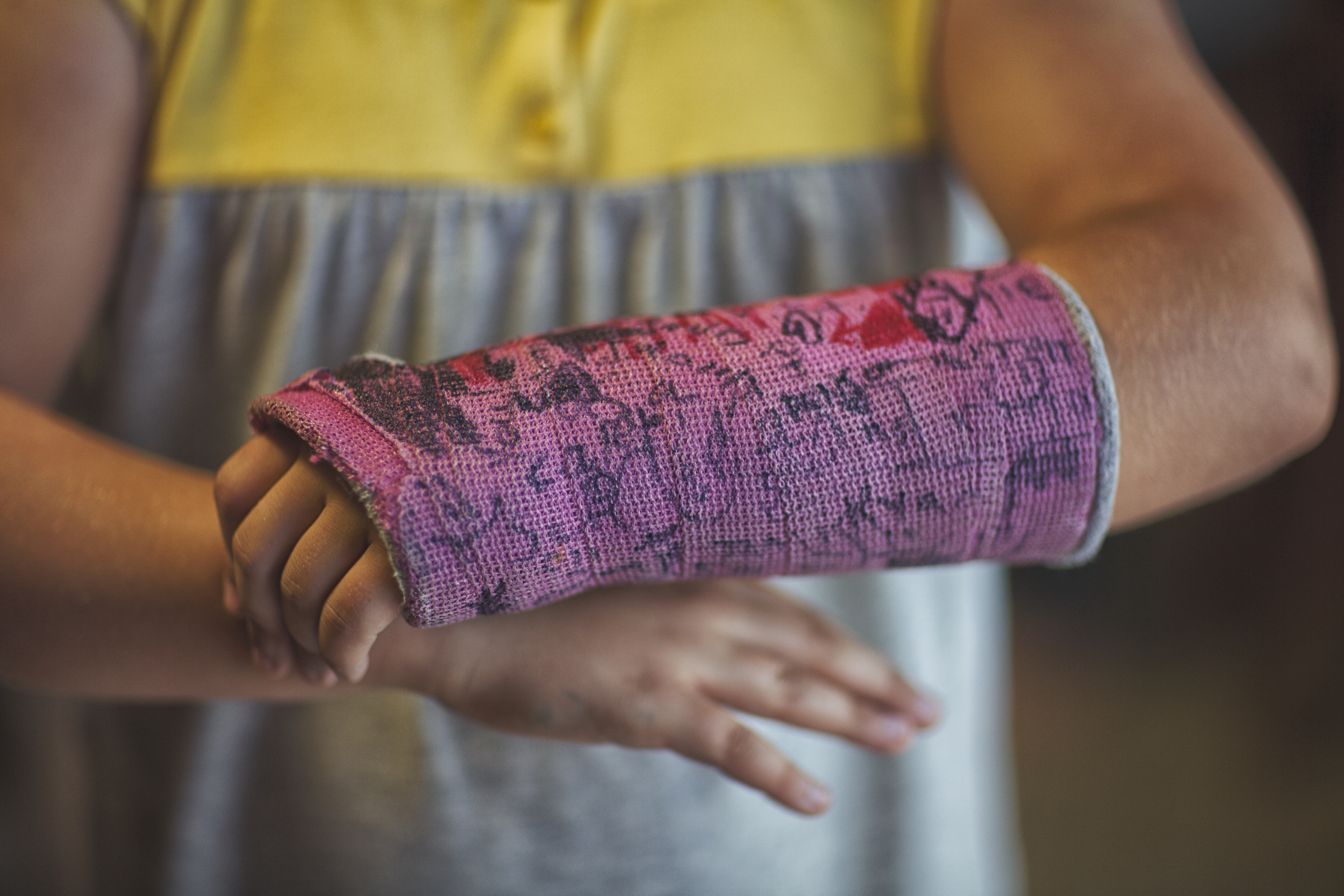 A person with a pink cast with a lot of writing on their arm