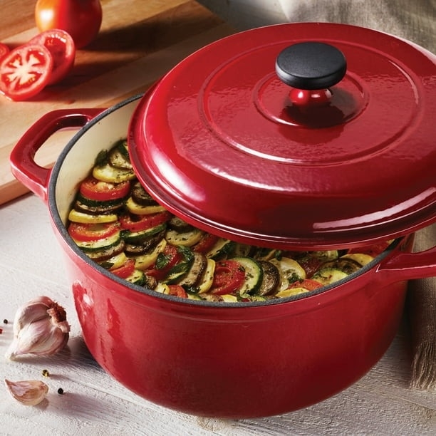 A red dutch oven with vegetables in it