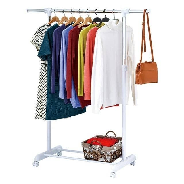the garment rack holding clothes, as a well as a bottom shelf for additional storage