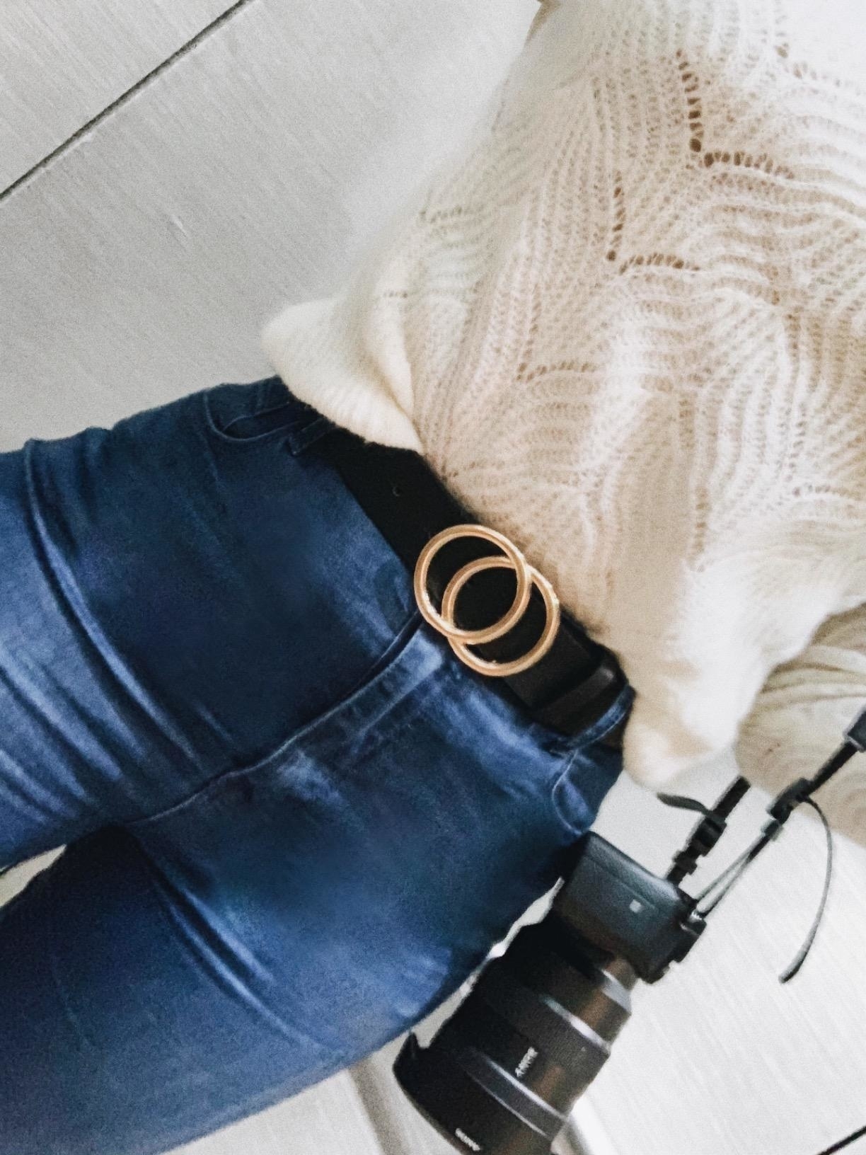 reviewer wearing faux leather belt with jeans and sweater