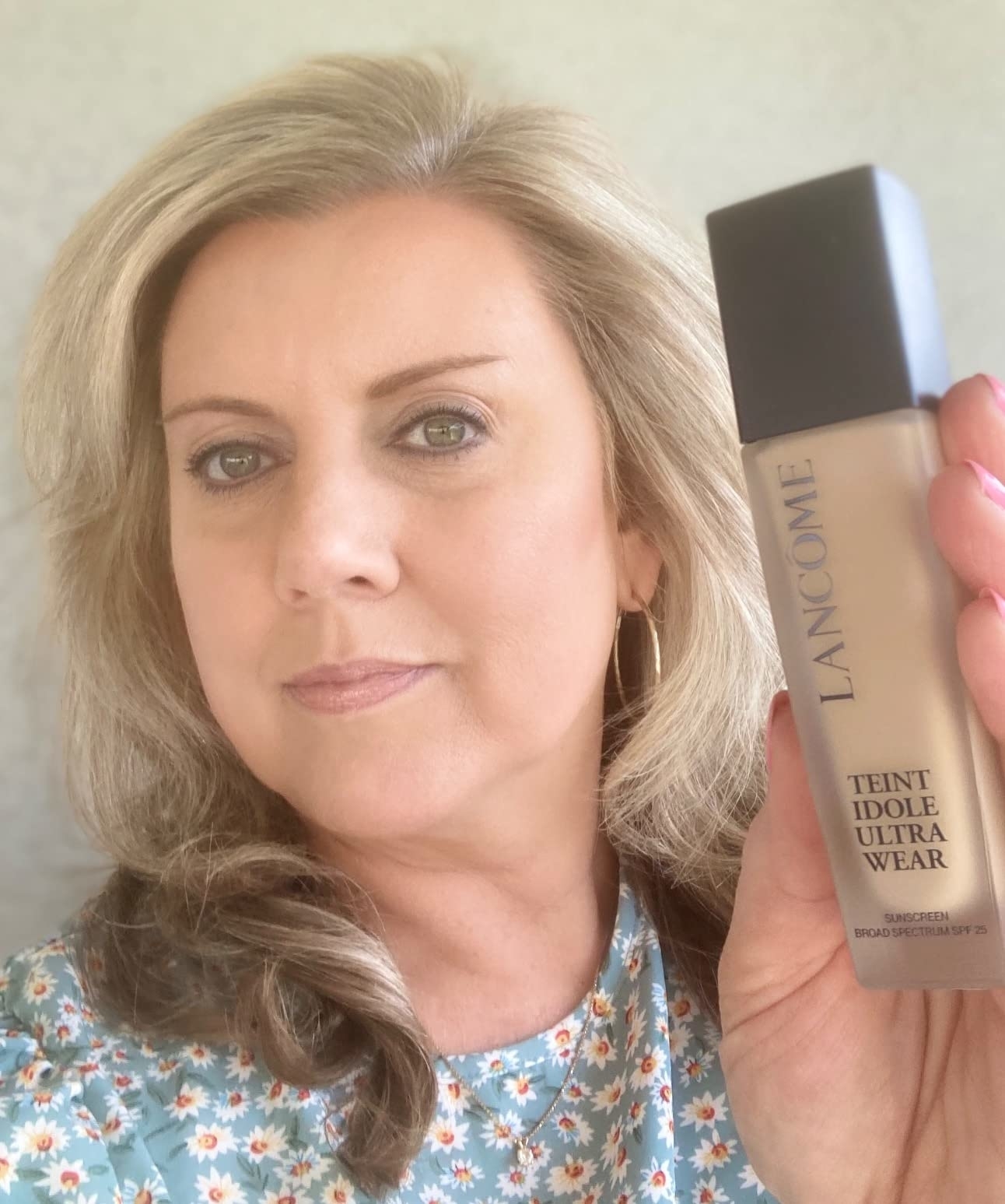 a reviewer wearing the foundation and holding the bottle of it